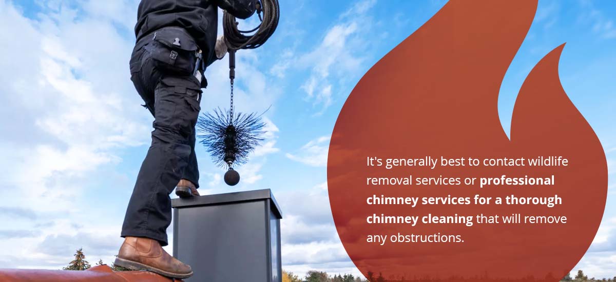 Man cleaning chimney while standing on a roof. 